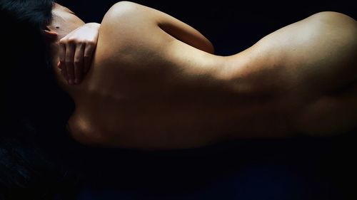 Close-up of woman lying down against black background