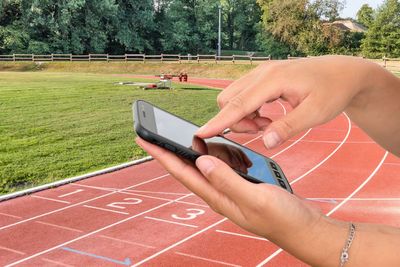 Midsection of man holding mobile phone in garden