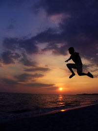 Silhouette person in sea against sky during sunset