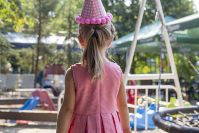 Rear view of girl standing against pink background