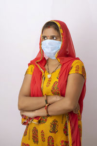 Close-up of woman wearing flu mask standing against white background
