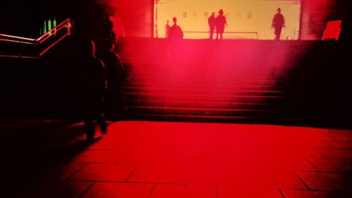 Silhouette people walking on sidewalk at night