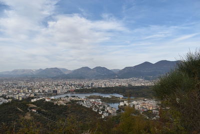 Aerial view of townscape by mountains against sky