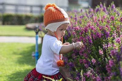 Side view of child standing by flowering plants