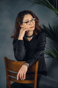 Woman leader in glasses posing in the studio sitting on chair