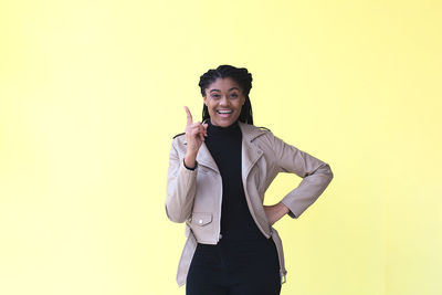 Portrait of smiling young woman against gray background