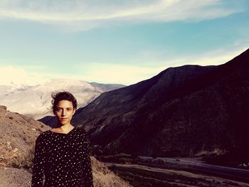 Portrait of young woman standing on mountain against sky