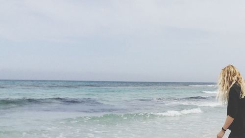 Rear view of man standing on beach against clear sky