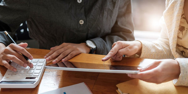 Midsection of woman holding smart phone while sitting on table