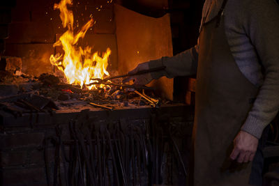 Latvian blacksmith working with open fire in furnace. the blacksmith forging hot iron in workshop