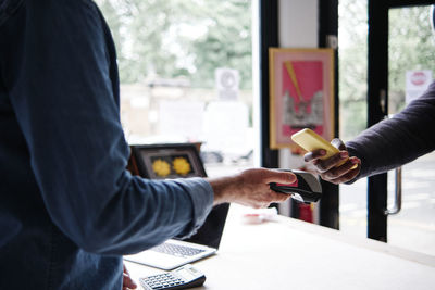 Male customer using smart phone while making contactless payment in store