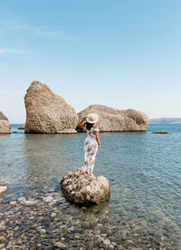 Rear view image of woman in long dress standing on beautiful beach on pag island in croatia.