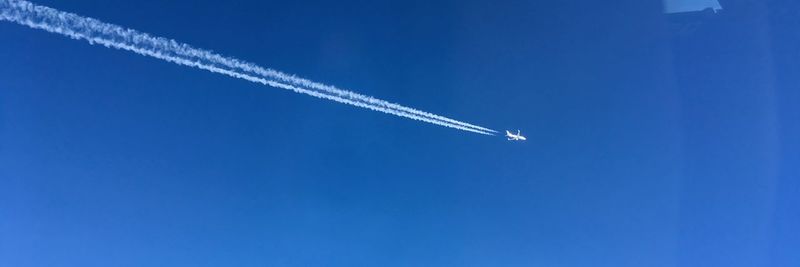 Low angle view of vapor trail against blue sky