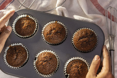 Top view of a tray full of homemade chocolate muffin cup cake held in hand