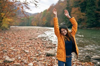 Portrait of man with arms raised standing in autumn