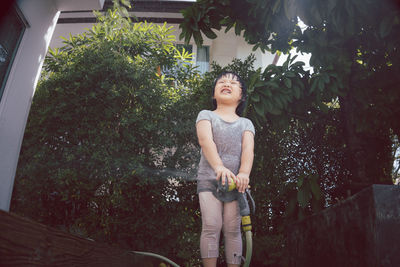 Young woman looking away while standing against trees