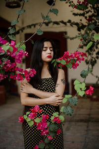 Portrait of beautiful woman standing by pink flower