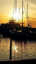 Sailboats moored at harbor during sunset