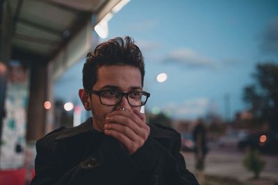 Young man looking away while sitting by window at cafe