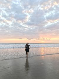 Woman on beach against sky during sunset