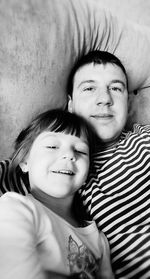 High angle portrait of father and daughter resting on sofa