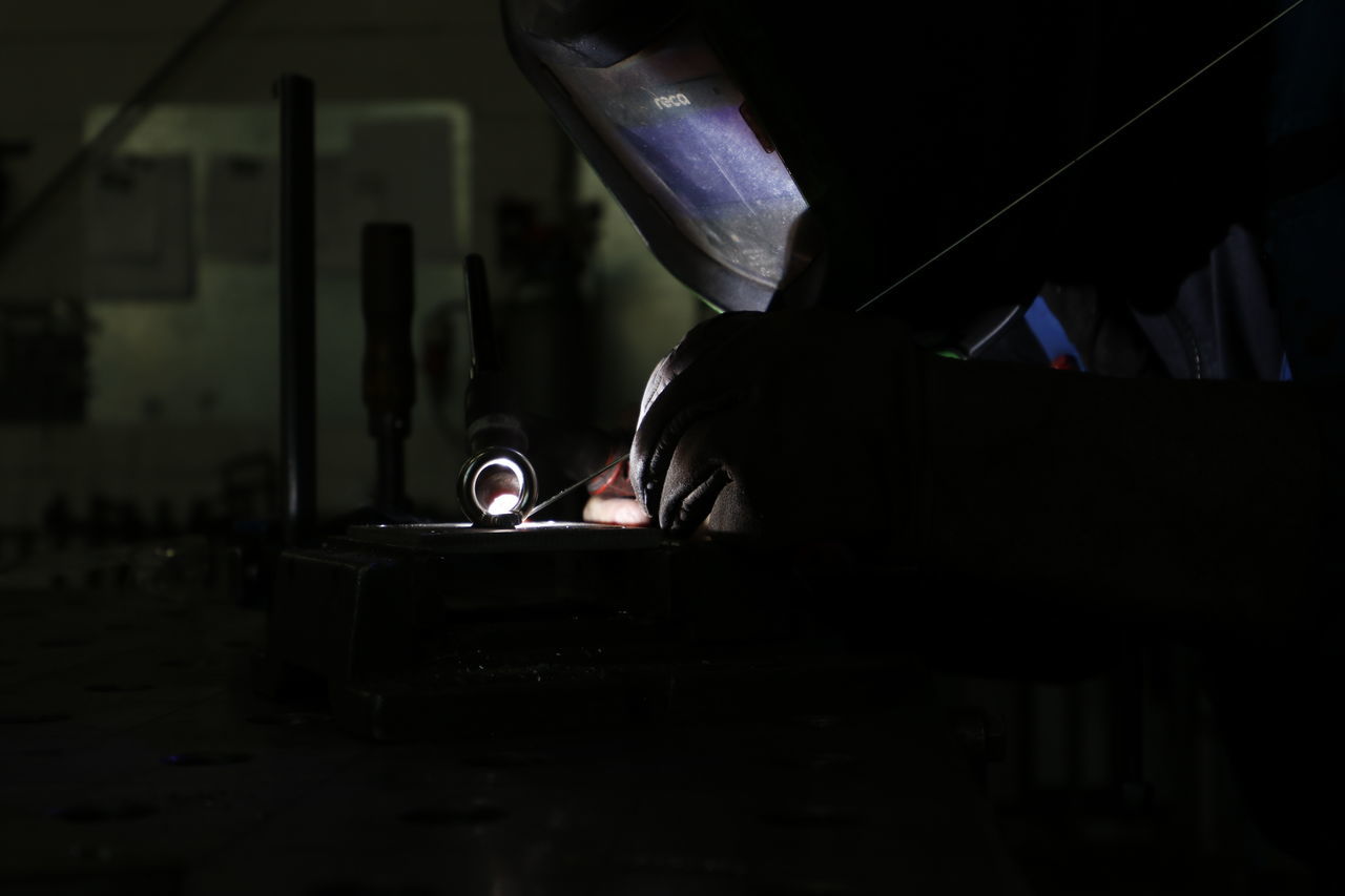 CLOSE-UP OF MAN WORKING ON TABLE IN DARK ROOM