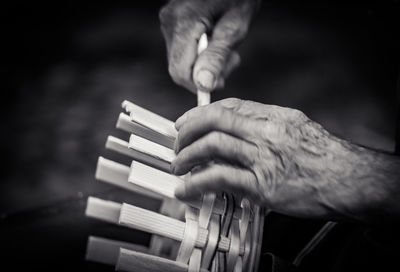 Cropped hands of man making wicker basket