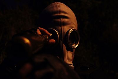 Close-up of person wearing protective mask in darkroom