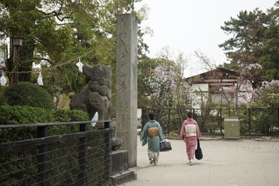 Rear view of people walking by plants