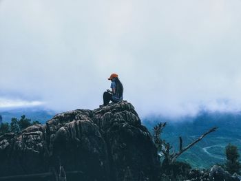 Low angle view of girl on rock against sky