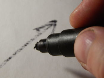 Close-up of person holding felt tip pen on paper