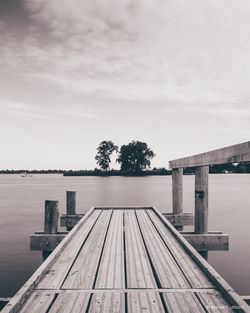 Wooden jetty on pier over lake against sky