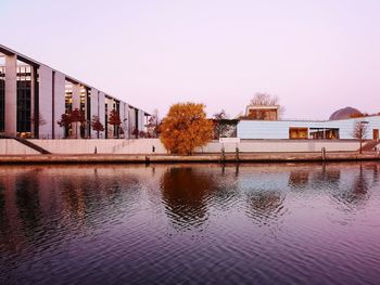 Buildings by lake against clear sky