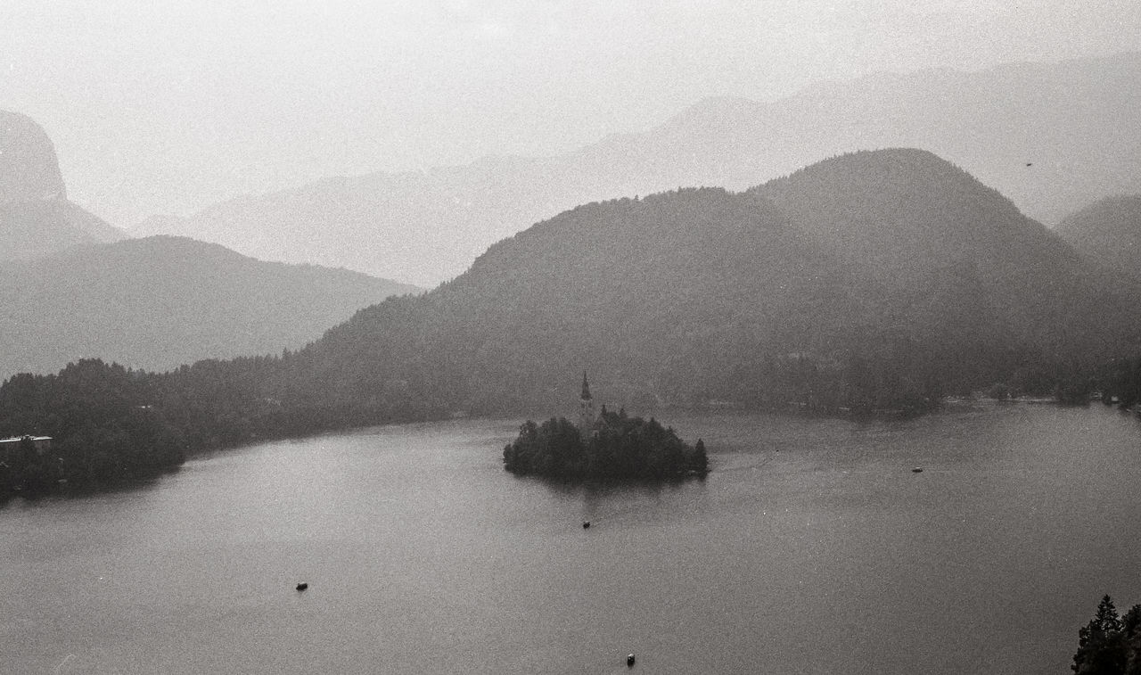 water, mountain, scenics - nature, fog, mist, tranquility, beauty in nature, black and white, nature, tranquil scene, tree, mountain range, sky, lake, monochrome, plant, morning, monochrome photography, no people, day, land, environment, outdoors, landscape, travel destinations, non-urban scene, haze, idyllic, travel, nautical vessel