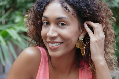 Close-up portrait of smiling young woman with curly hair