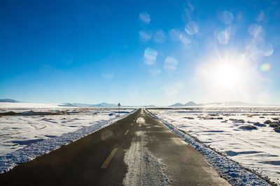 Snow covered landscape against blue sky