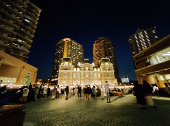 People at illuminated buildings in city at night