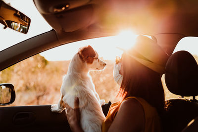 Close-up of woman wearing mask holding puppy in car