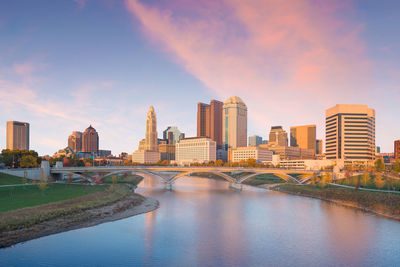 River by buildings against sky during sunset