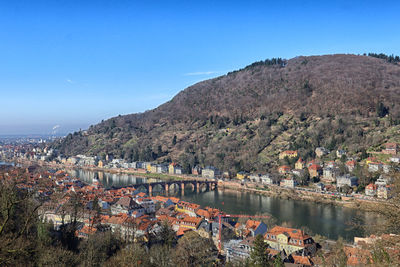 High angle view of townscape by sea against clear blue sky