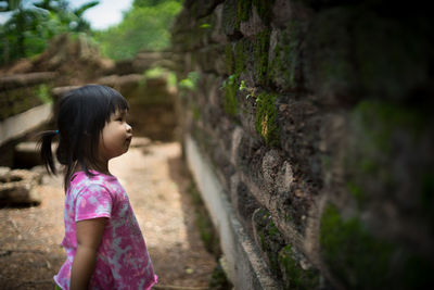 Side view of girl looking at brick wall