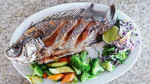 High angle view of fish and vegetable served on table