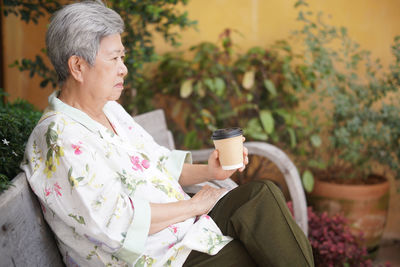 Young woman using mobile phone while sitting on sofa at park