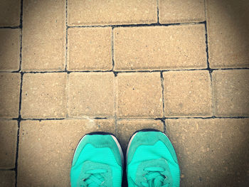 Low section of person wearing shoes while standing on paving stone