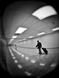 Fish-eye view of man pulling luggage at airport