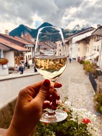 Cropped hand of woman holding wineglass against houses in town