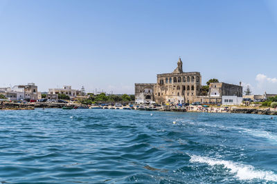 View of buildings by sea against blue sky