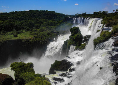 Scenic view of waterfall in forest against sky