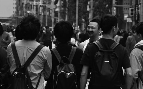 Rear view of people standing on street in city