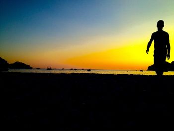 Silhouette man on beach against sky during sunset